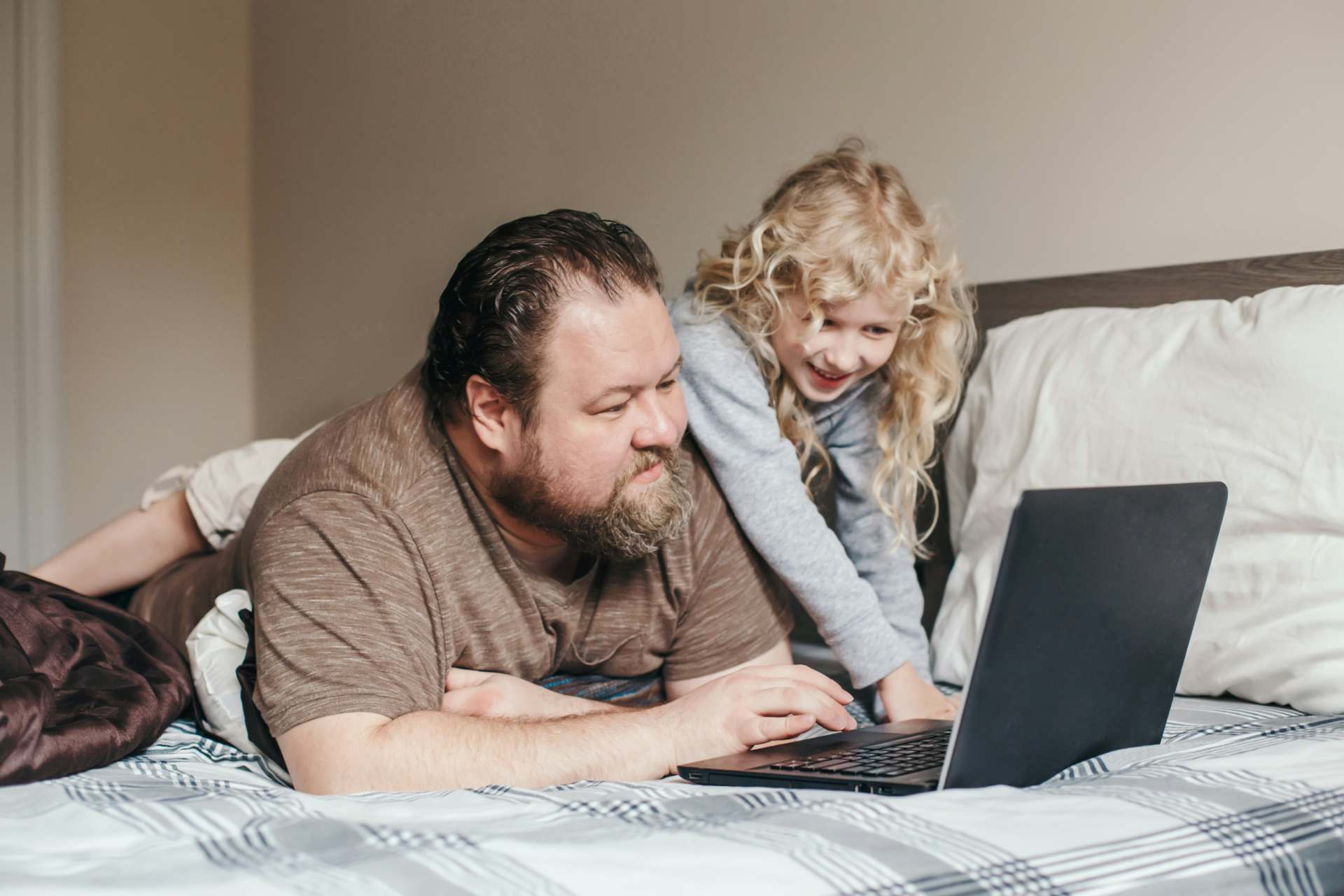 dad with daughter on bed using laptop